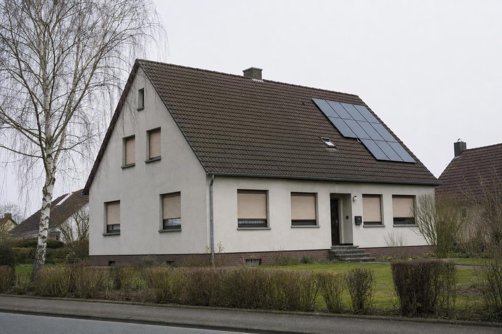 Einfamilienhaus aus den 1970er-Jahren mit alten Rollläden und kleiner Solaranlage auf dem Ziegeldach – der typische Sanierungsfall in Deutschland